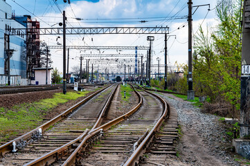 Railroad tracks with rails and electric power wires for trains. Rails and sleepers. High-voltage supply voltage wires. Railway equipment. Trains and locomotives. Direction of movement.