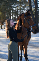 Obraz premium Young girl with horse on winter forest road