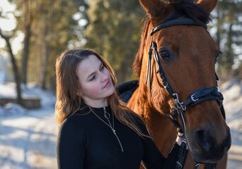 Obraz premium Young girl with horse on winter forest road