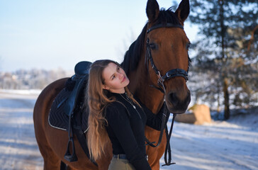 Obraz premium Young girl with horse on winter forest road
