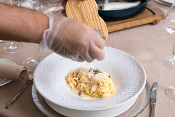 grana padana cheese pasta with truffles. chef is cooking spaghetti in parmesan head. selective focus