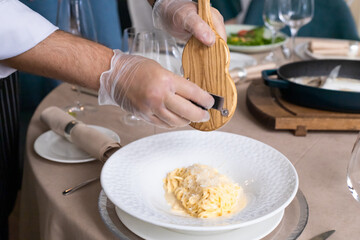 grana padana cheese pasta with truffles. chef is cooking spaghetti in parmesan head. selective focus