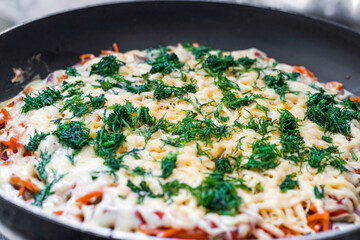 There is a pizza on the frying pan sprinkled with herbs.