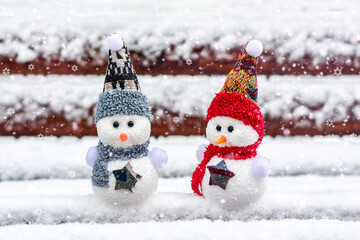 Merry christmas and happy new year greeting card with copy space Happy two little snowmen in red, blue cap and scarf standing in winter snow background Xmas fairytale Hello January, February concept