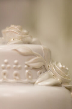 White rose wedding cake decoration on unfocused white background. Full frame, selective focus, extreme close-up. 
