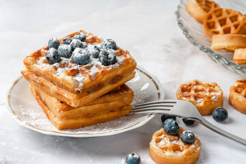 belgian waffles with berries on a light background. sweet waffles with blueberries for breakfast