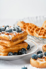 belgian waffles with berries on a light background. sweet waffles with blueberries for breakfast