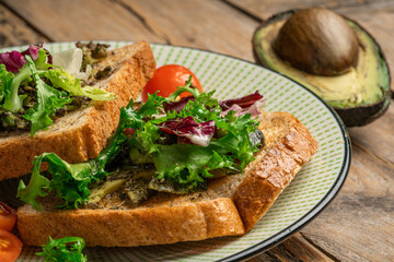 toast with avocado. vegetarian breakfast. Vegan or Vegetarian Toast with mashed avocado, arugula served on wooden board