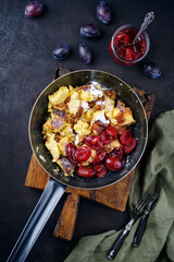 Traditioneller österreichisch Kaiserschmarren mit Zwetschgen und Rosinen serviert als Draufsicht in einer rustikalen Bratpfanne 