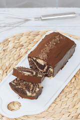 Chocolate marble loaf cake with chocolate glaze. On white cafe table.