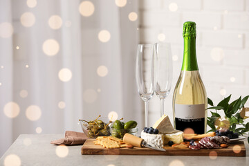 Bottle of sparkling wine, glasses and delicious snacks on grey table indoors. Space for text
