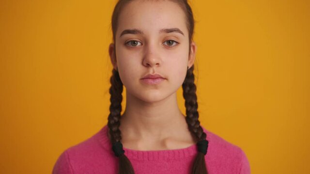 Cheerful girl with pigtails opening her eyes at the camera in the yellow studio