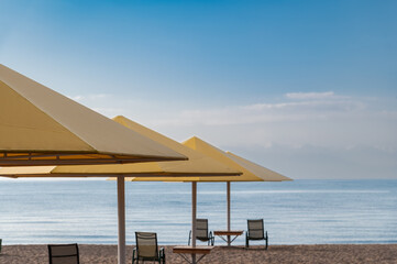 Seascape with sandy beach, umbrella and deck chairs..