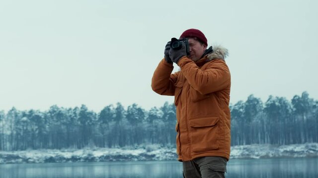 Adventure photographer takes pictures of a lake in the winter forest. on a professional camera