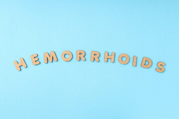 Concept of hemorrhoids with wooden letters on blue background