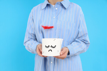 Woman holds toilet paper with feather on blue background. Hemorrhoids concept