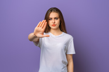 Portrait of serious brunette girl showing stop taboo sign, extending hand palm to prevent...