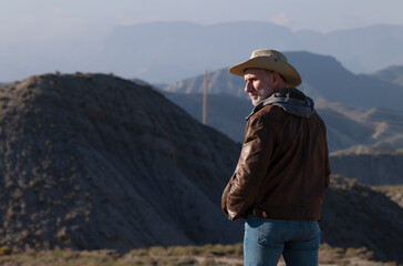 Adult man in cowboy hat looking at view of Tabernas Desert, Almeria, Spain