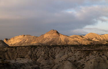 Landscape of Tabernas Desert, Almeria, Spain, in the morning with sunlight and shadow, against cloudy sky