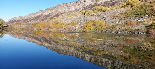 Reflection of the shore in the clear blue water of the river. Autumn, vacation, fishing. Silence