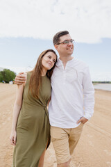 Obraz premium a couple of a man and a woman are walking on the beach or running along the sand along the seashore. beautiful and young European man and woman on a romantic walk in nature, a couple in love, a happy
