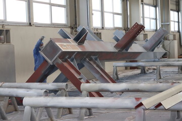 The painter is working to painting the steel structure with spray gun at industrial factory