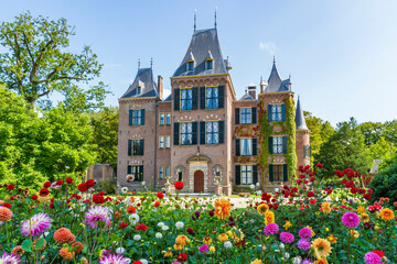 The front view of a beautiful castle with the colorful dahlias in the foreground in a park in...