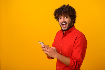 Funny surprised trendy guy suddenly read message on his mobile phone and expressing shock amazement, unbelievable news on smartphone. Studio shot isolated - obrazy, fototapety, plakaty