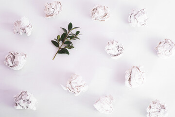 overhead shot of crumpled paper in oder and green twig among on white background. zero waste concept