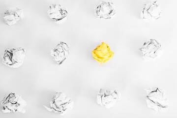 overhead shot of crumpled paper in oder and yellow one standing out on white background. great idea...