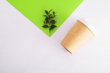 coffee cup of reusable materials with green twig next to colored paper on white background. zero waste concept. ecology. replacement for plastic cups. Copy space, go green, isolated
