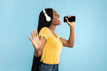 African American Lady Singing Holding Phone Near Mouth, Blue Background