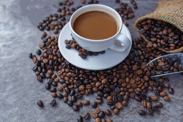 Coffee cup and roasted coffee beans in brown bag, top view.