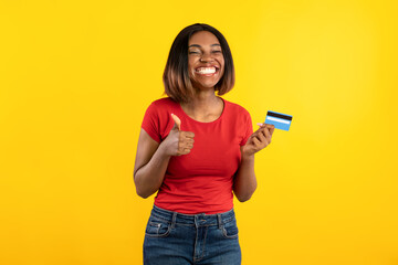 Cheerful Black Female Showing Credit Card And Like, Yellow Background
