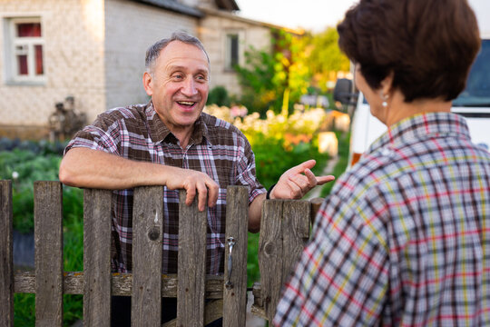 Neighbors Man And Woman Chatting Near The Fence In The Village