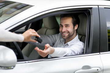 Close up female hand gives car key to male hand in dealership