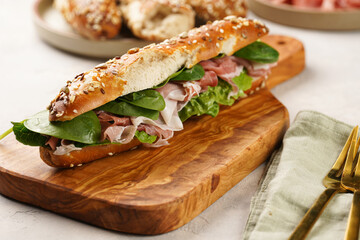 Long sandwich in brown lye bread sticks garnished with oats , pork slices prosciutto, hard cheese...