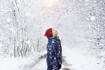 A child enjoys the snowfall in winter - walks in the winter forest