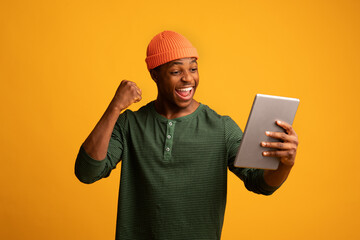 Online Success. Cheerful African American Guy With Digital Tablet Celebrating Success
