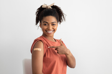 Positive black woman pointing at medical band on shoulder