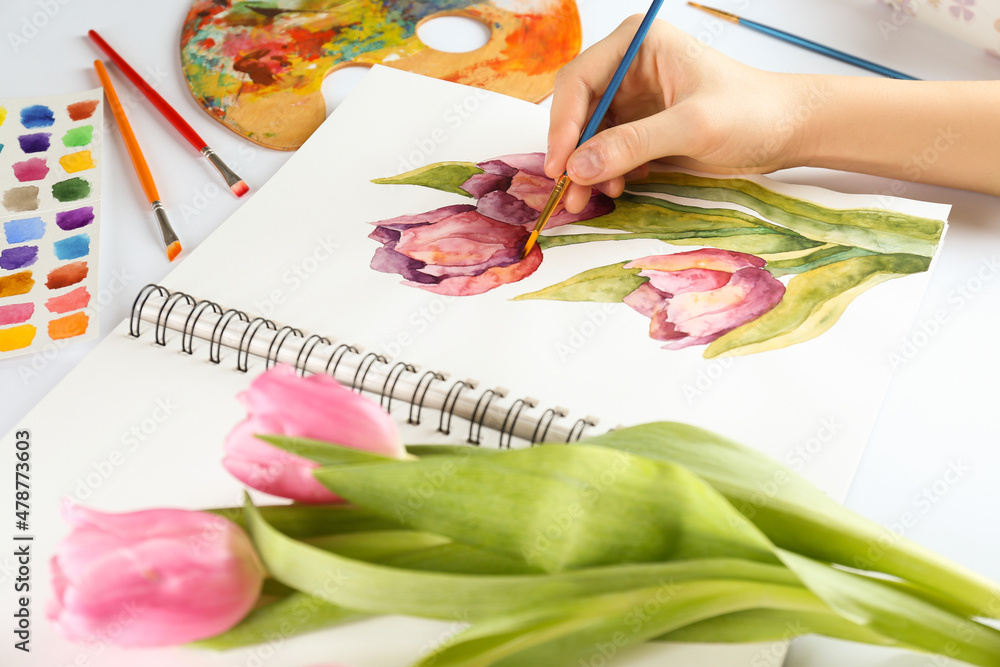 Canvas Prints Woman painting tulips in sketchbook at white table, closeup