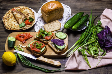 Sandwiches with salmon and greens. Sandwich with cottage cheese and basil and cucumber. Dark...