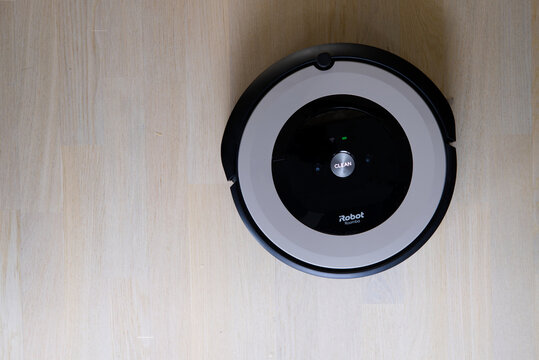 iRobot Roomba - modern autonomous robotic vacuum cleaner on beige wooden floor