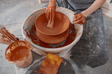 Handmade artist shaping clay bowl with instrument in art studio