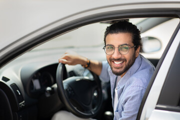 Portrait of happy arab guy getting into brand new car