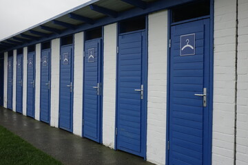Blue and white bathing huts at the North Sea protection dike (dyke) on a grey and stormy day, Burhave, Lower Saxony, Germany