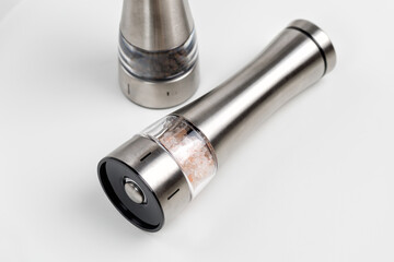 Spice mills for salt and pepper.Electric and metal. On a white table