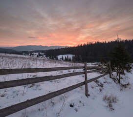 Small alpine village and winter snowy mountains in first sunrise sunlight around, Voronenko, Carpathian, Ukraine.