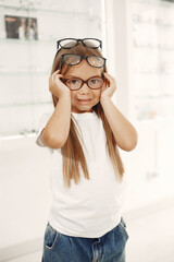 Little girl choosing glasses at optics store