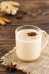 Masala chai with spices in a glass cup on a wooden table. Selective focus.